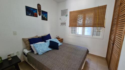 - une chambre avec un lit doté d'oreillers bleus et d'une fenêtre dans l'établissement Flat 47 SUN HOUSE Maresias, à Maresias