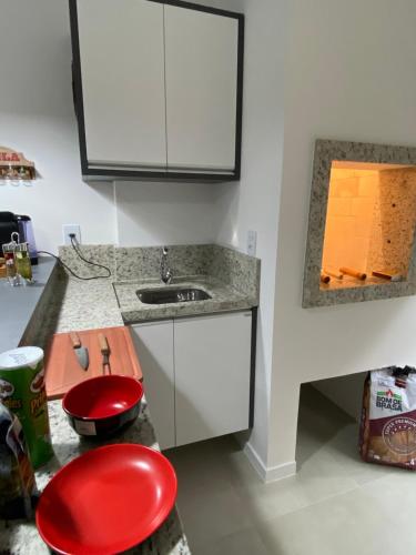 cocina con fregadero y taburete rojo en Espaço Benguela - Ingleses Florianópolis en Florianópolis