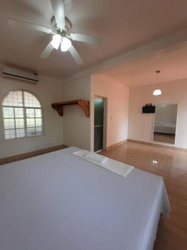 1 dormitorio con cama blanca y ventilador de techo en Ethos Inn, en Juigalpa