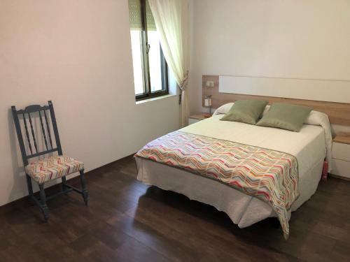 1 dormitorio con 1 cama grande y 1 silla en El Mirador de la Villa en Puebla de Sanabria
