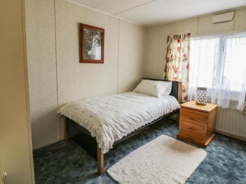 a small bedroom with a bed and a window at The Lodge in Attleborough