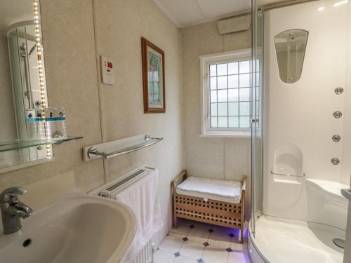 een badkamer met een bad, een wastafel en een douche bij The Lodge in Attleborough