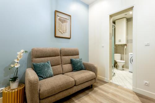 un salon avec un canapé et une salle de bains. dans l'établissement StayLib - GARIBALDI 2 PIECES PORTE DE MONTMARTRE, à Saint-Ouen