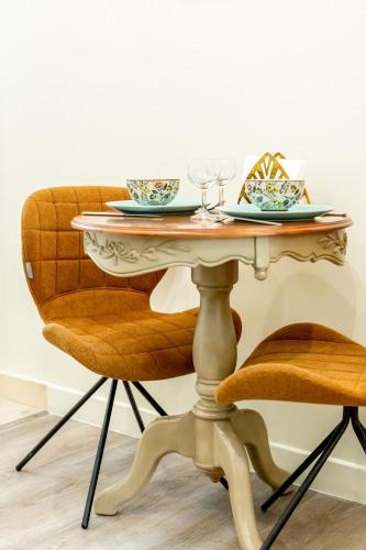 une table et deux chaises avec des assiettes et des verres dans l'établissement StayLib - GARIBALDI 2 PIECES PORTE DE MONTMARTRE, à Saint-Ouen