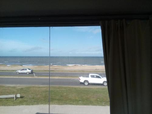 a window with a view of the ocean and cars at Playa Dorada, fte mar, gran 2 amb 4 pax, quincho parrilla in Santa Clara del Mar