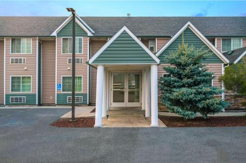 a house with a pine tree in front of it at Motel 6-Idaho Falls, ID - Snake River in Idaho Falls
