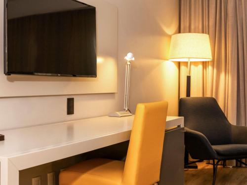 a living room with a television and a lamp at Novotel Florianopolis in Florianópolis