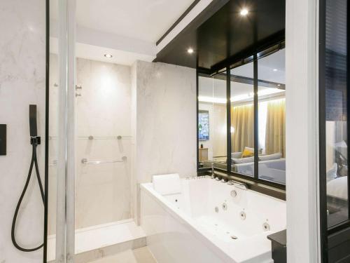 La salle de bains est pourvue d'une baignoire et d'une douche. dans l'établissement Mercure Bordeaux Aéroport, à Mérignac