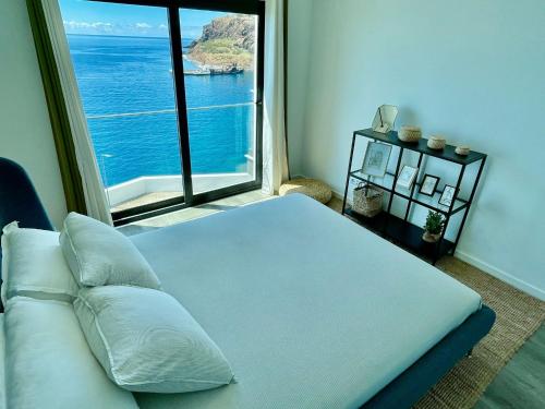 um quarto com uma cama e uma grande janela em Ocean Cliff Apartment em Santa Cruz - Madeira