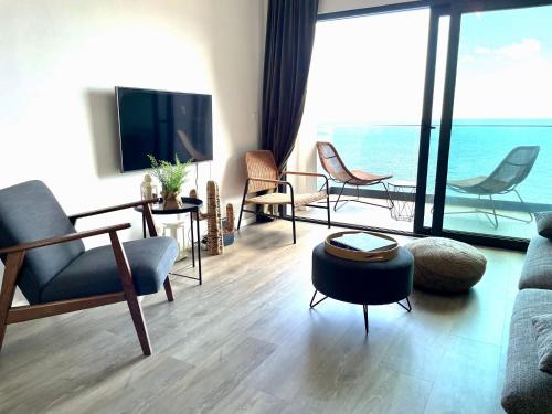 a living room with chairs and a couch and a tv at Ocean Cliff Apartment in Santa Cruz