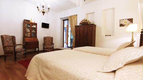 a bedroom with two beds and a dresser and a window at Hotel Boutique Casa Montalvo Cuenca in Cuenca