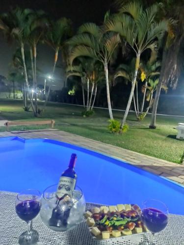 a bottle of wine and wine glasses next to a pool at Pousada Tapera in Penedo