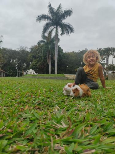 a woman sitting in the grass with a dog at Pousada Tapera in Penedo