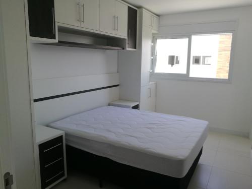 Piccola camera bianca con letto e finestra di EA-Apto com vista do mar em Praia dos Ingleses a Florianópolis