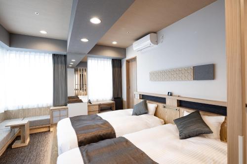 a hotel room with two beds and a bathroom at Hotel Grand Cocoe Kurashiki in Kurashiki