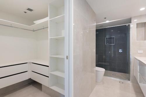 a white bathroom with a shower and a toilet at Allunga Stunning Beach Side Apartment in Gold Coast