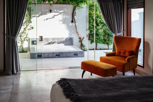 a bedroom with a bed and a chair and a window at Kamil Villas in Seminyak