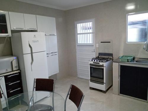eine Küche mit einem weißen Kühlschrank und einem Glastisch in der Unterkunft Casa Beira Rio Xingó in Canindé de São Francisco