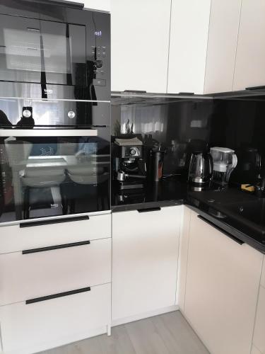 a kitchen with white cabinets and black appliances at Apartament Portowy in Wilkasy