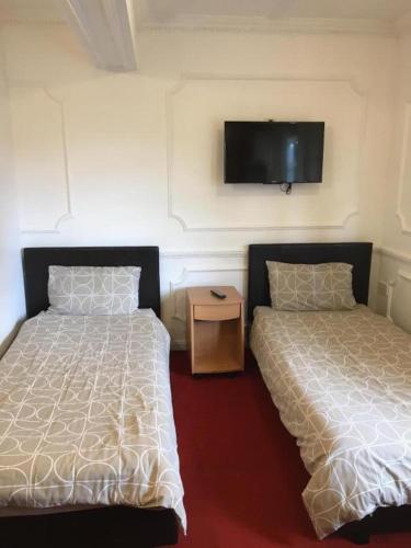 a bedroom with two beds and a tv on the wall at Hatfield SAVE-MONEY Rooms - 10over10 for PRICE! in Hatfield