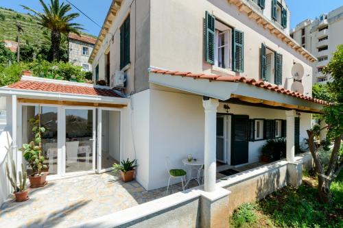 a white house with green shutters and a patio at Apartments Dubrovnik Palm Tree Paradise in Dubrovnik