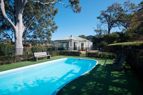 a swimming pool with a bench and a house at Mistress Block Vineyard in Pokolbin