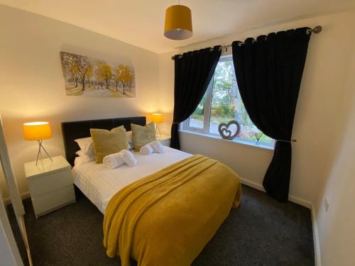 a bedroom with a bed with a yellow blanket and a window at Druid House Lodge in Inverness