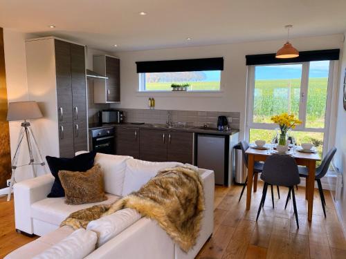 a living room with a white couch and a kitchen at Druid House Lodge in Inverness