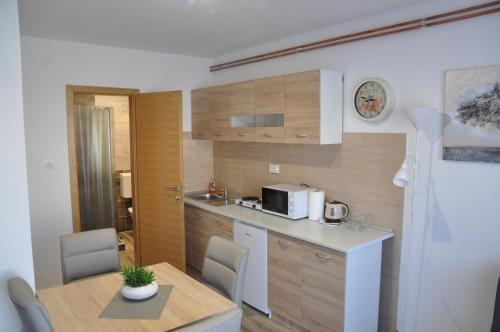 a small kitchen with a table and a microwave at Apartmani Ana Vukovar in Vukovar