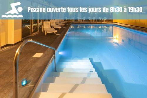 a large swimming pool with chairs in a building at Le Studio Saint Martin - Piscine & Spa - Aéroport in Toulouse
