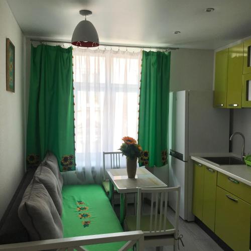 a kitchen with green curtains and a table with a couch at MaryLu home in Lviv