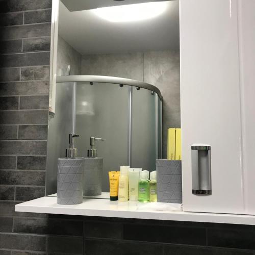 a bathroom with a shelf with bottles of soap and a shower at MaryLu home in Lviv
