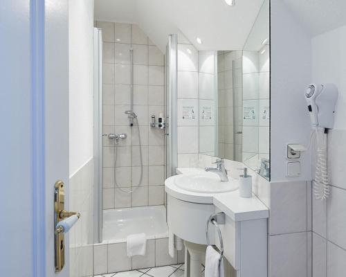 a white bathroom with a shower and a sink at Landhotel & Gasthof Cramer in Warstein