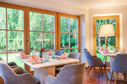 uma sala de jantar com mesas, cadeiras e janelas em Hotel Ziegleder em Rottach-Egern