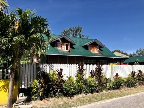 a house with a green roof and a white fence at Ambiance Villa in La Digue