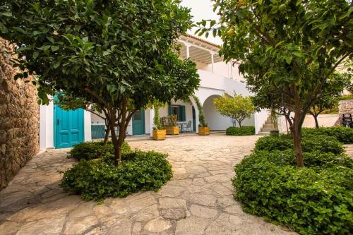 a courtyard with trees in front of a house at Aria Apartments in Spetses