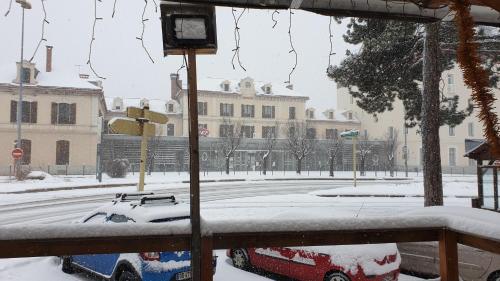 a snow covered street with a car parked in front of a building at Hotel de la Gare in Briançon