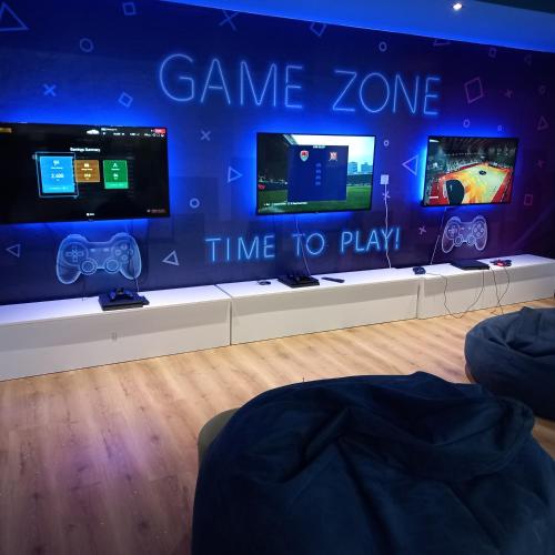 a game zone with three monitors on a wall at Family Resort Urania in Baška Voda