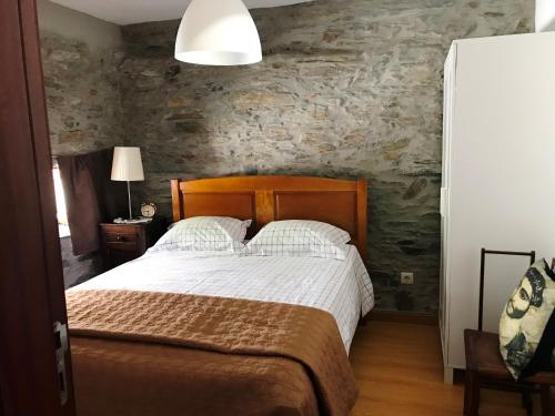 um quarto com uma cama e uma parede de pedra em Casa da Caroline em Freixo de Espada à Cinta