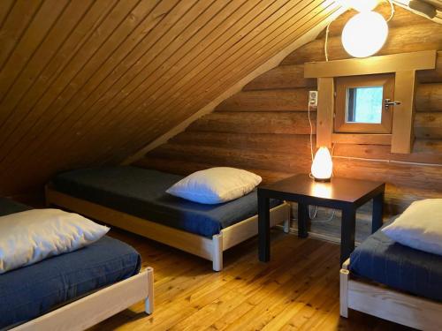 a room with two beds and a table in a cabin at Mökki Jyväskylä in Nyrölä