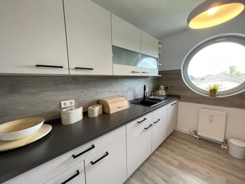 a kitchen with white cabinets and a large window at Apartment Rooftop in Dresden