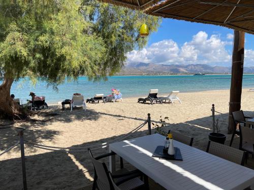 a table and chairs on a beach near the water at Coralli Rooms & Restaurant in Elafonisos