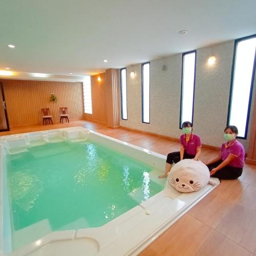 two people wearing masks sitting next to a swimming pool at Sriracha Orchid Hotel in Si Racha