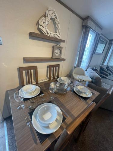 a wooden table with plates and wine glasses on it at Luxury Static Home 2 Bed Sleeps 6 in Great Yarmouth