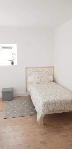 a bed in a room with a white wall at Les 3 mômes in Pontorson
