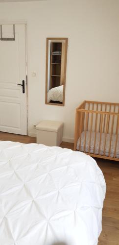 a bedroom with a white bed and a mirror at Les 3 mômes in Pontorson
