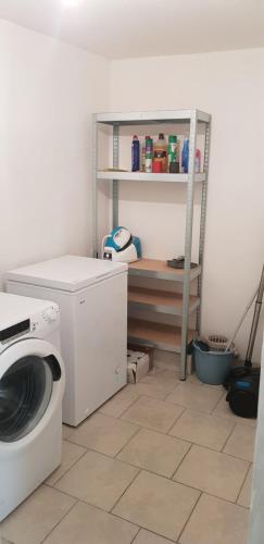 a laundry room with a washing machine and a shelf at Les 3 mômes in Pontorson