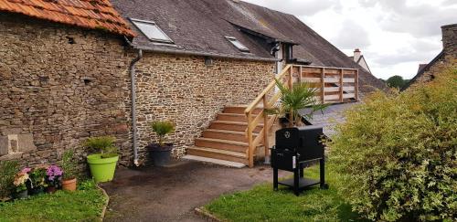 a brick building with a wooden staircase next to a house at Les 3 mômes in Pontorson