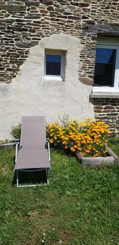 a bench sitting in front of a building with flowers at Les 3 mômes in Pontorson