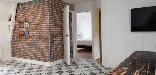 a room with a brick wall and a tv at Les 3 mômes in Pontorson